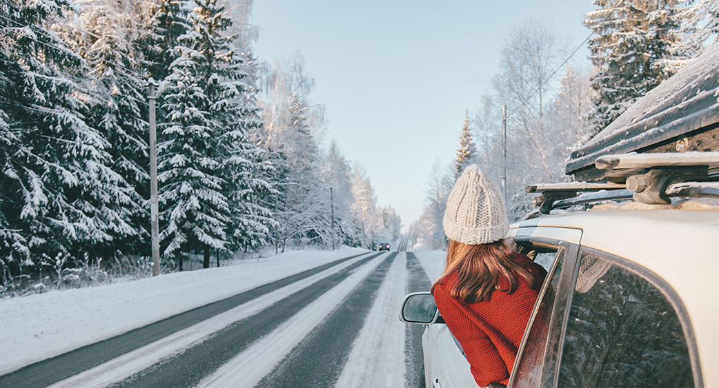 Car in the snow, passenger in red coat and knit cap looking out the window